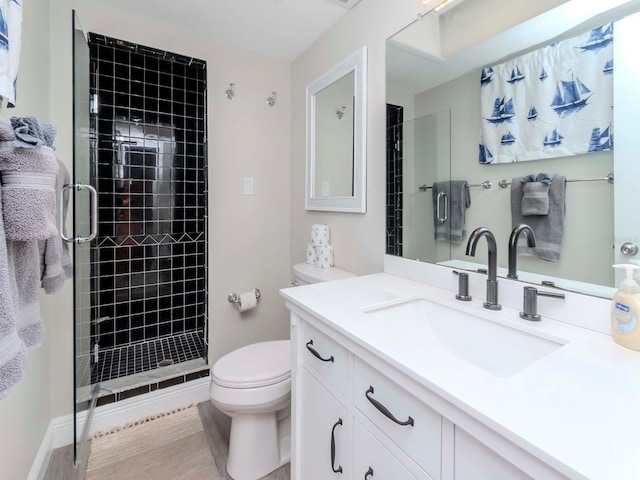 bathroom featuring a shower stall, toilet, vanity, and baseboards