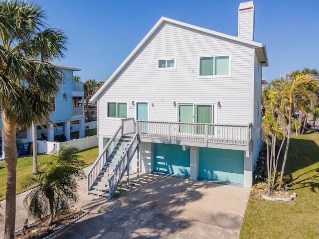 rear view of property with stairs, a yard, a garage, and driveway