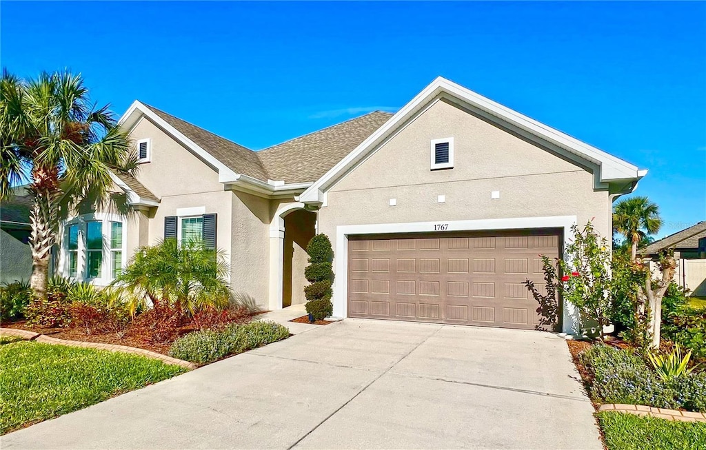 view of front facade featuring stucco siding, an attached garage, and driveway