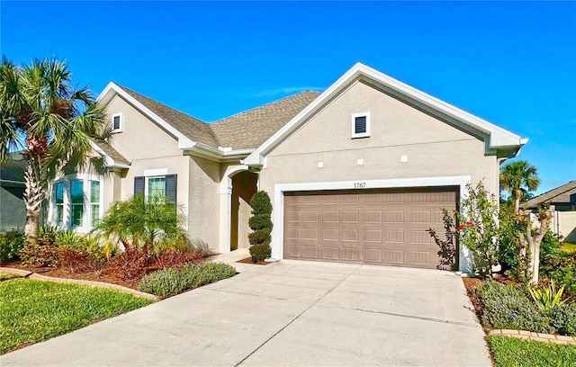 view of front facade featuring stucco siding, an attached garage, and driveway