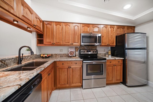 kitchen featuring brown cabinets, light stone countertops, stainless steel appliances, and a sink