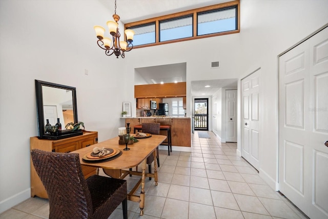 dining space with baseboards, visible vents, light tile patterned flooring, a towering ceiling, and a chandelier