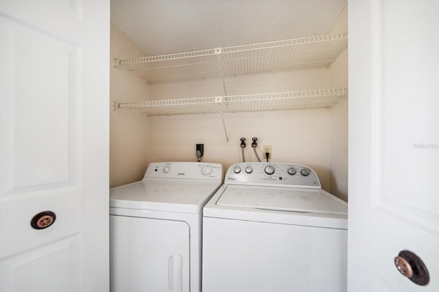 washroom featuring washer and dryer, laundry area, and a textured ceiling