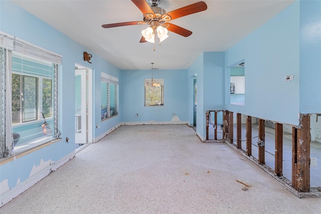 unfurnished room with ceiling fan with notable chandelier