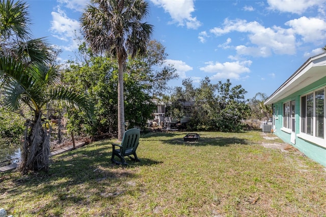 view of yard with central air condition unit and an outdoor fire pit