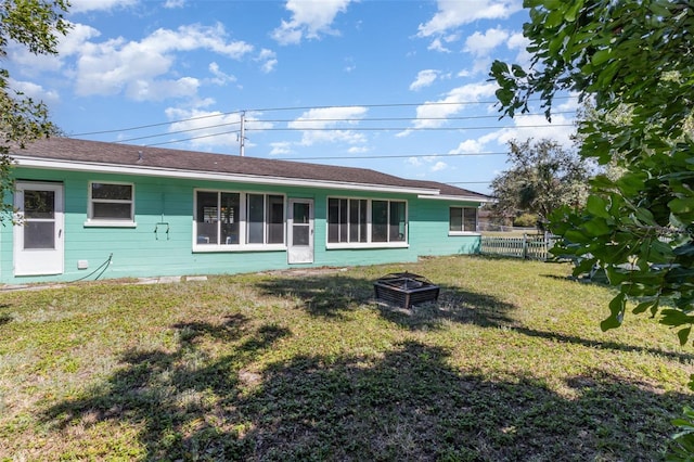 rear view of property featuring fence and a lawn