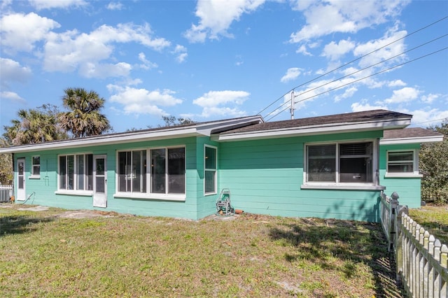 rear view of house with central air condition unit, a lawn, and fence