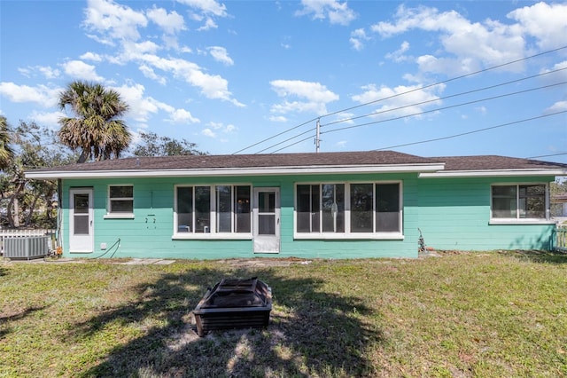 back of house with cooling unit, a lawn, concrete block siding, and fence