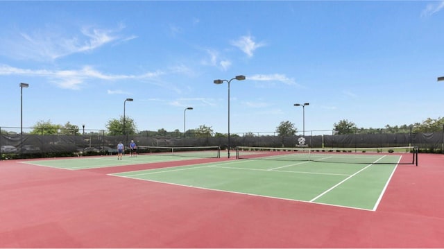 view of tennis court featuring community basketball court and fence