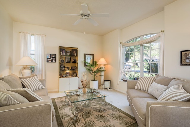 living area with a ceiling fan, carpet flooring, a healthy amount of sunlight, and baseboards