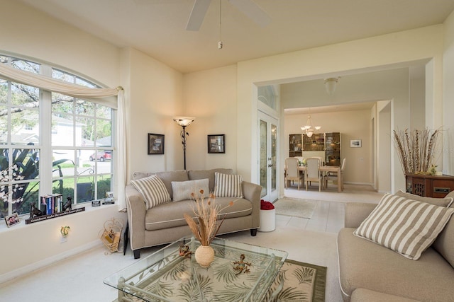 living room featuring ceiling fan with notable chandelier and baseboards