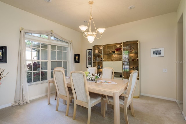 dining room with baseboards, light colored carpet, and a chandelier