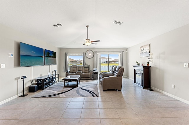 living room with light tile patterned floors, visible vents, baseboards, and ceiling fan