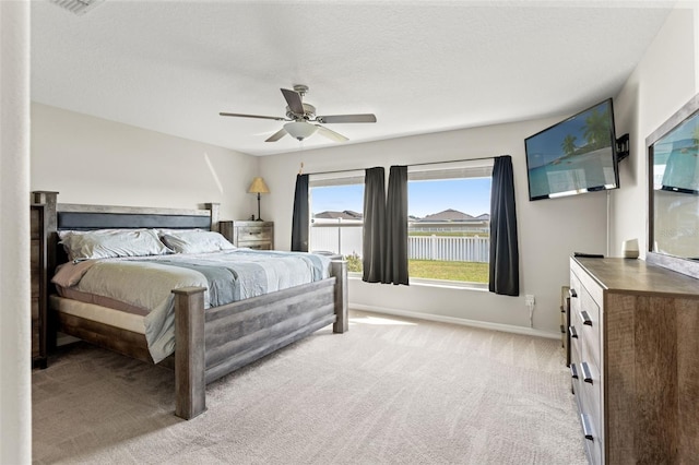 bedroom with a textured ceiling, a ceiling fan, baseboards, and light carpet