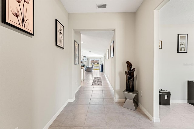 hallway featuring light tile patterned flooring, baseboards, and visible vents