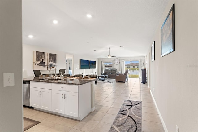 kitchen featuring a ceiling fan, white cabinetry, dark stone counters, a sink, and stainless steel dishwasher