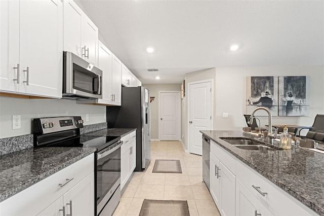 kitchen featuring a sink, white cabinetry, stainless steel appliances, dark stone counters, and light tile patterned flooring