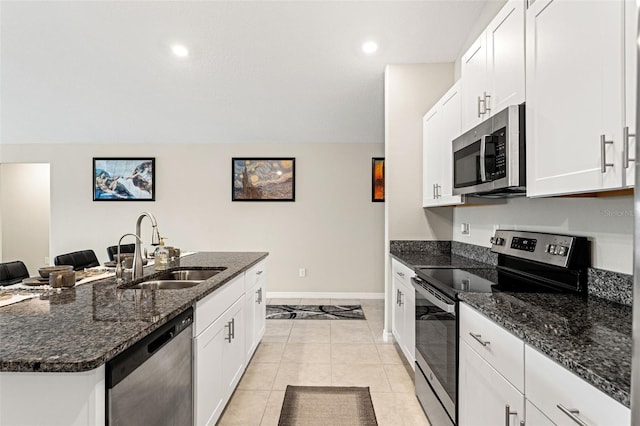 kitchen with dark stone countertops, baseboards, appliances with stainless steel finishes, and a sink