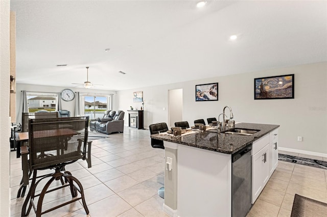 kitchen featuring dark stone counters, lofted ceiling, light tile patterned flooring, a sink, and stainless steel dishwasher