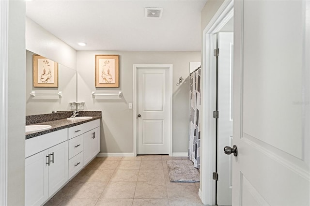 full bath with visible vents, a sink, tile patterned flooring, double vanity, and baseboards