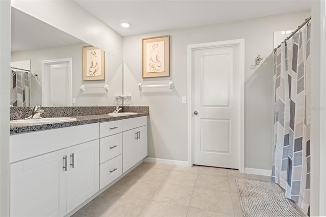 bathroom featuring a sink, baseboards, double vanity, and tile patterned flooring