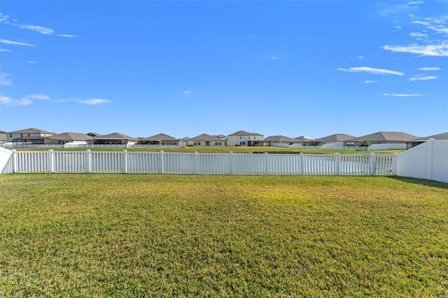 view of yard featuring a fenced backyard, a residential view, and a water view