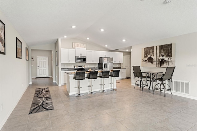 kitchen with visible vents, white cabinetry, appliances with stainless steel finishes, and a breakfast bar