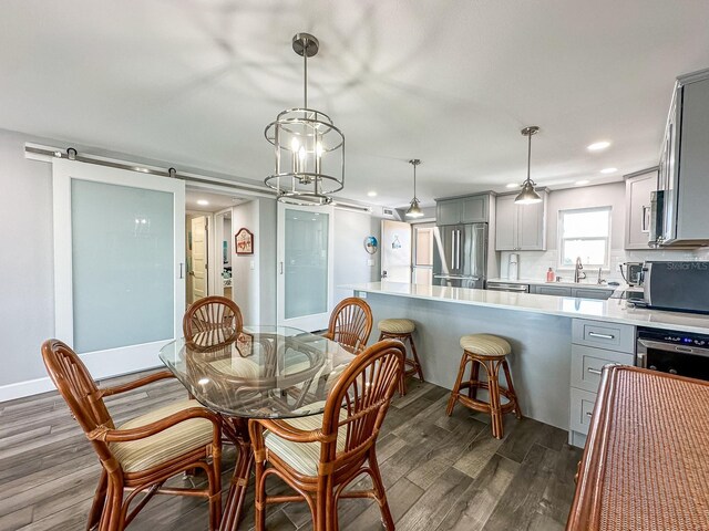 dining room with recessed lighting, a barn door, baseboards, and dark wood-style flooring