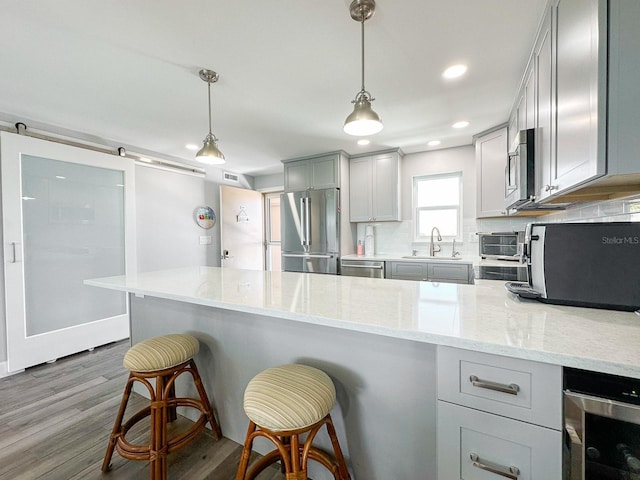 kitchen with dark wood finished floors, beverage cooler, decorative backsplash, appliances with stainless steel finishes, and a sink