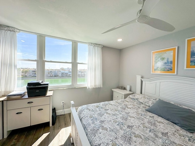 bedroom featuring dark wood-type flooring, multiple windows, a ceiling fan, and baseboards