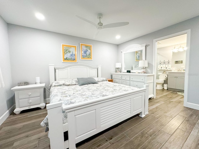 bedroom featuring ceiling fan with notable chandelier, wood finished floors, baseboards, and connected bathroom