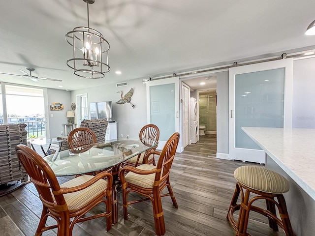 dining room featuring a ceiling fan, a barn door, dark wood-style floors, and visible vents