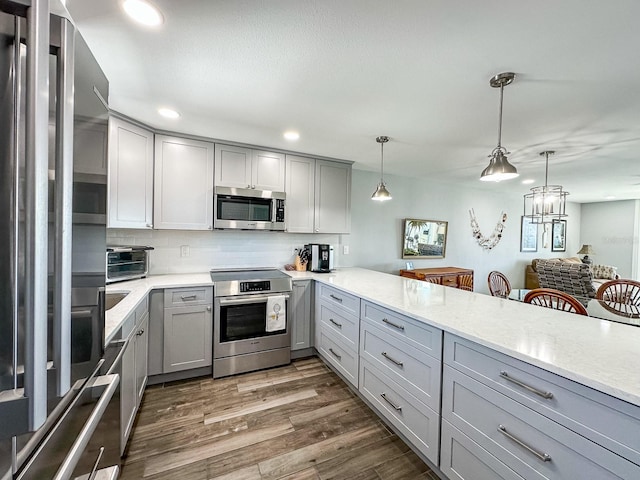 kitchen featuring dark wood-style floors, recessed lighting, gray cabinets, stainless steel appliances, and decorative backsplash