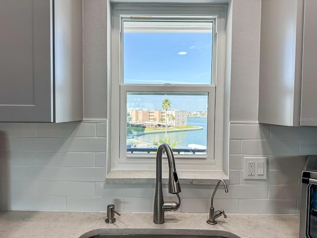 kitchen featuring a sink, decorative backsplash, a wealth of natural light, and a textured wall