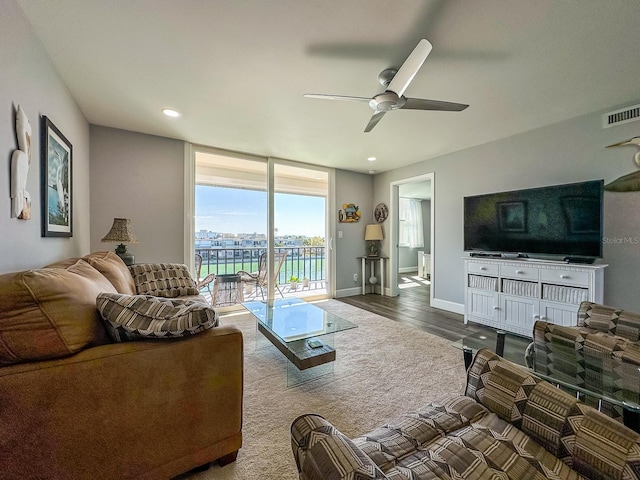 living area featuring visible vents, baseboards, a wall of windows, a ceiling fan, and dark wood-style flooring