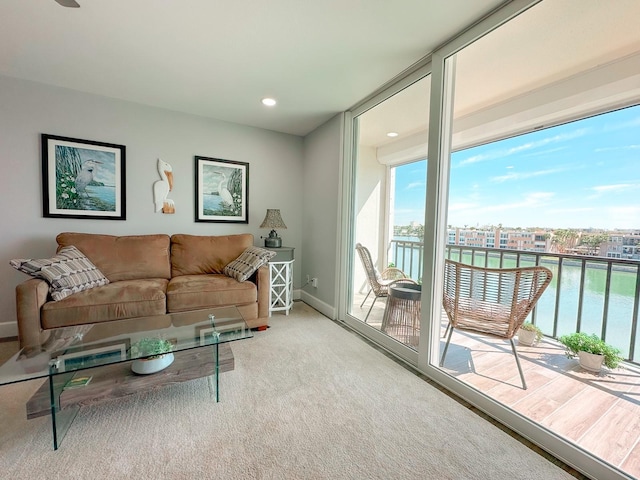 living area featuring floor to ceiling windows, plenty of natural light, baseboards, and a water view