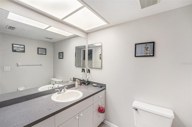 bathroom with visible vents, toilet, and vanity