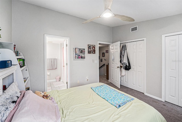 bedroom featuring a ceiling fan, visible vents, multiple closets, ensuite bathroom, and carpet flooring