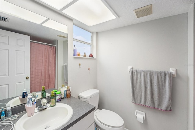 full bath with visible vents, toilet, vanity, and a textured ceiling