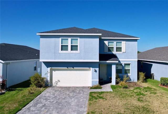 view of front facade with decorative driveway, an attached garage, a front lawn, and stucco siding