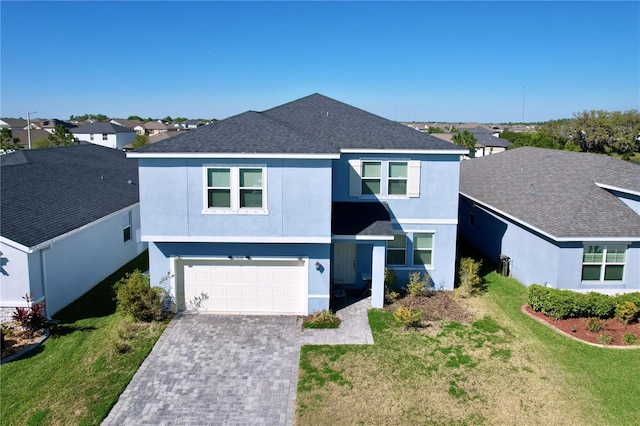 view of front of house featuring a front yard, roof with shingles, stucco siding, decorative driveway, and a garage