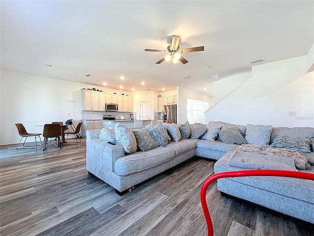 living area featuring dark wood-type flooring, baseboards, visible vents, and ceiling fan