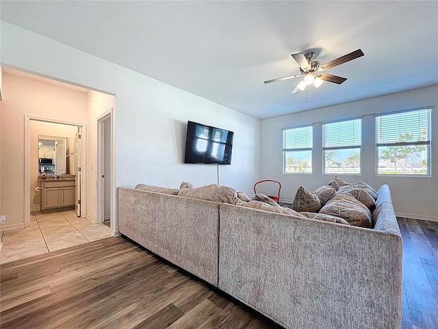 living room featuring baseboards, a ceiling fan, and light wood finished floors