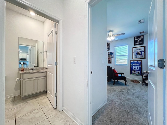 corridor with light carpet, visible vents, and baseboards