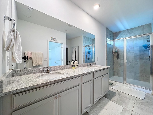 bathroom with double vanity, visible vents, a stall shower, and a sink