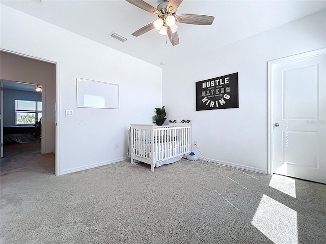 bedroom featuring visible vents, a ceiling fan, carpet floors, a nursery area, and baseboards