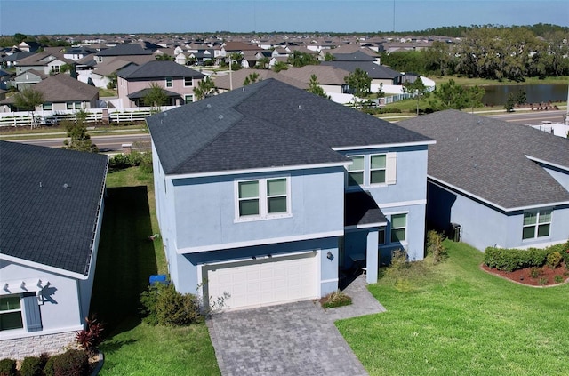 exterior space with driveway, roof with shingles, an attached garage, a front lawn, and a residential view