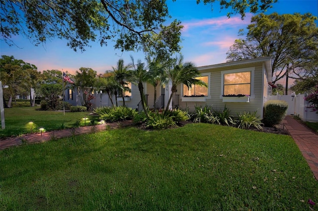 view of front of house with a lawn and fence