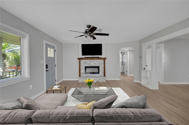 living area featuring a fireplace, a ceiling fan, light wood-type flooring, and baseboards