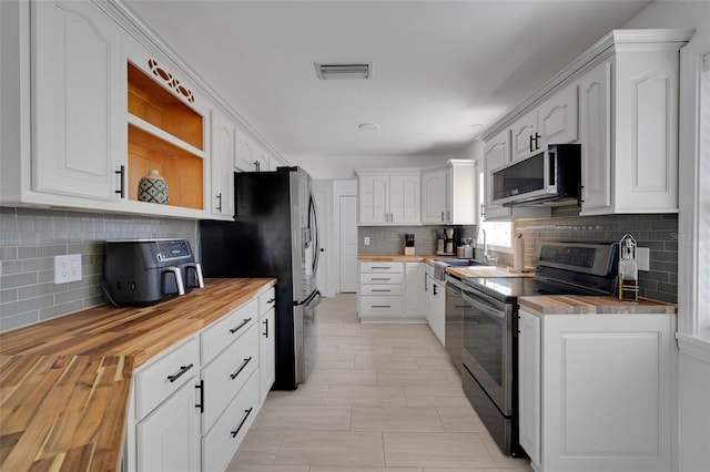 kitchen with open shelves, visible vents, stainless steel appliances, and wood counters